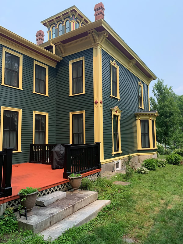 Side view of an historic home with deck and bay window.