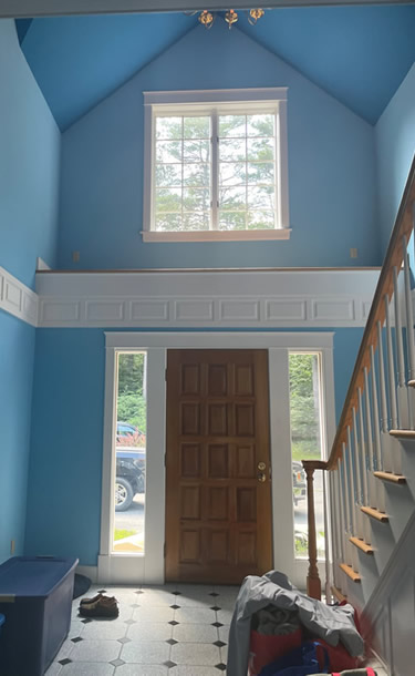 Blue entrance way with cathedral ceilings before painting has begun.